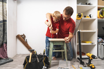 The father shows the little son how to tighten the screws with a screwdriver.
