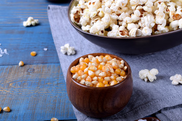 Unpopped corn kernels for making popcorn in a wooden cup on blue table