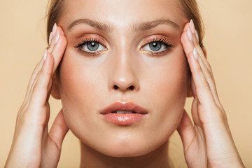 Image of young half-naked woman touching her temples and looking at camera