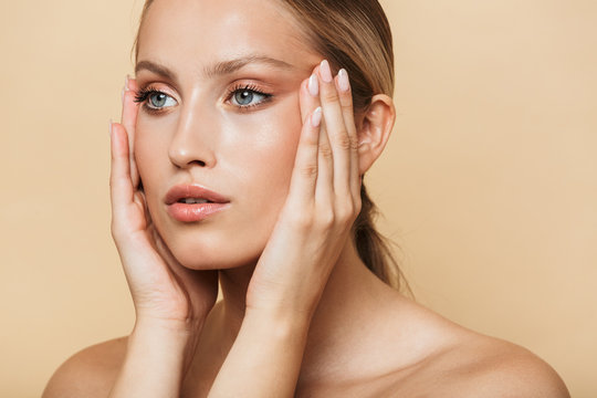 Image of blonde half-naked woman touching her temples and looking aside