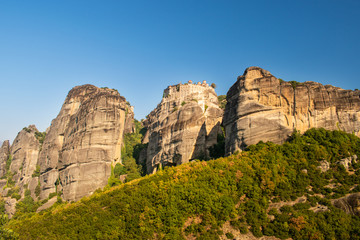 Fototapeta na wymiar Monastery Meteora Greece. Stunning panoramic landscape. View of mountains and green forest against epic blue sky with clouds. UNESCO heritage object.