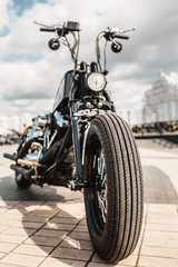 Obraz na płótnie Canvas The front wheel of the motorcycle with a drum brake and a cable to it is the front fork with a shock absorber and a spring on a homemade motorcycle in a vintage style