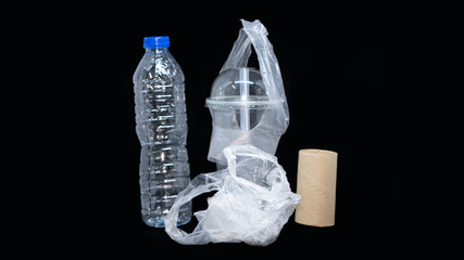 Plastic water bottles and plastic mugs with brown paper on a black background