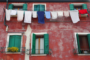 Fototapeta na wymiar Colorful clothes hanging on a clothesline from a window to dry in the sun in Venice, Italy