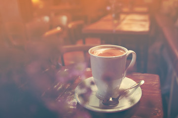 Close up white coffee latte cup on table near window with sun flare