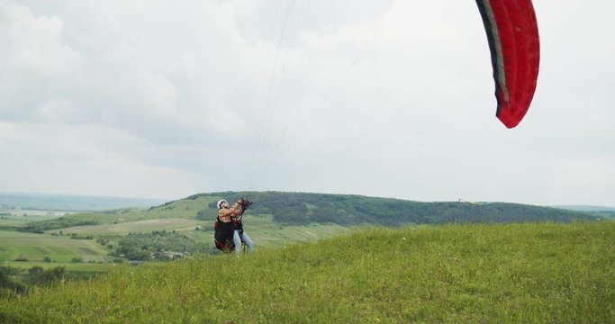 Man preparing parachute for paragliding above beautiful countryside valley, risky hobby, adventures
