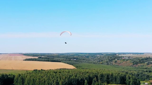 Person training with a paraplane over fields.