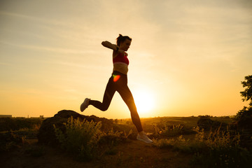 Fototapeta na wymiar Young Beautiful Woman Running on the Mountain Trail at Hot Summer Sunset. Sport and Active Lifestyle.