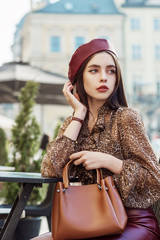 Outdoor, street style, fashion portrait of elegant, luxury woman wearing faux leather dark red...