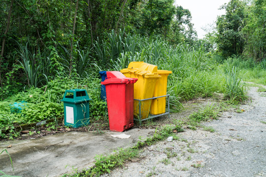 Abandoned garbage bin beside street background. Deserted trash can in the forest park