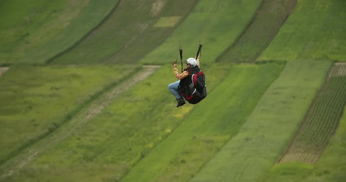 Paraglider flying over beautiful rural valley enjoying scenery and favorite hobby, recreation activity