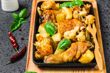 One sheet pan dinner, roasted vegetables, chicken legs, dark background. Selective focus, space for text.