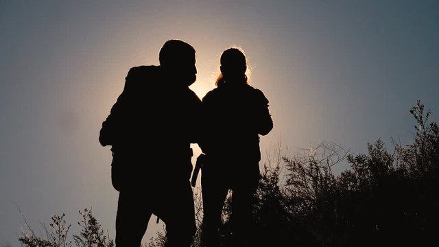 teamwork tourists travel concept slow motion video. hiking silhouette happy family couple man and girl go hiking climbing a mountain. walking on nature. tourists with backpacks traveling lifestyle