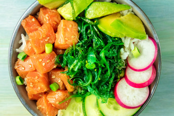 Salmon poke with avocado, wakame and cucumber, overhead close-up shot