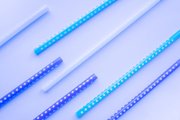 Multi-colored straws for drinking cocktail on a blue background, holiday concept, top view.