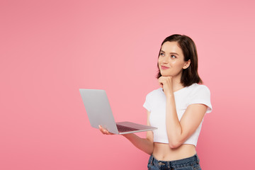 Fototapeta premium dreamy smiling pretty girl using laptop isolated on pink