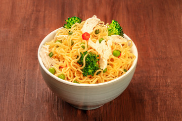 Soba noodles with vegetables and chicken meat on a dark rustic wooden background