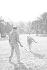 Black and white photo of Happy senior couple playing badminton in park