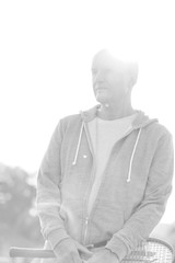 Black and white photo of Active senior man playing badminton with tennis racket in park