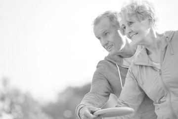 Black and white photo of Loving active couple throwing flying disc together in park
