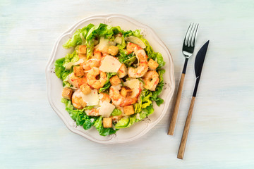 Shrimp Caesar salad with Parmesan cheese, croutons and lettuce, shot from above