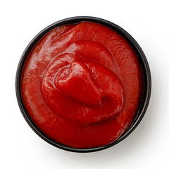Tomato ketchup in small black ceramic dish isolated on white. Top view.