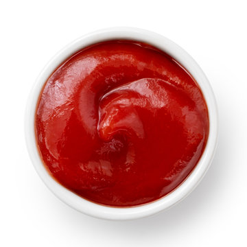 Tomato ketchup in small white ceramic dish isolated on white. Top view.