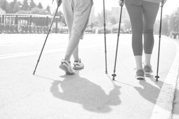 Black and white photo of Senior couple with hiking poles walking on footpath at park