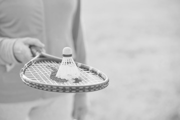 Black and white photo of senior woman with shuttlecock on tennis bat in park