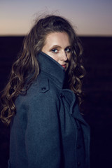 woman in grey coat and black dress in field at sunset