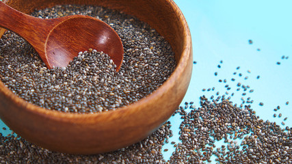 Nutritious chia seeds on a blue background. chia seeds in bowl and a spoon on kitchen table top...