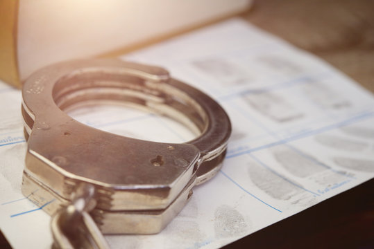 Crime and violence concept.Police Handcuffs on fingerprints crime page file
