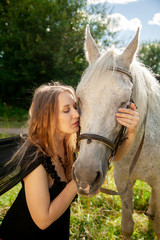 Fototapeta premium Beautiful caucasian young girl walking with a horse and enjoys summertime in countryside.