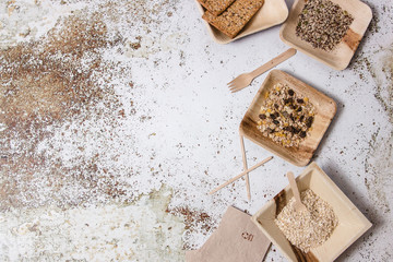 Bowls, dishes,forks, napkins and different plastic free tableware displayed in the right side of a table with different ingredients.
