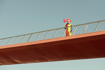 scary clown with a red balloon on a bridge © nito