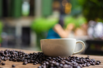 Latte coffe in white cup with roasted coffee bean on wood