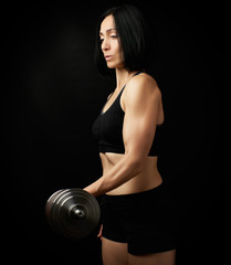 young woman of Caucasian appearance holds steel type-setting dumbbells in her hands