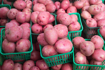 a pile of red skinned potatoes in baskets in a market vendor's stall