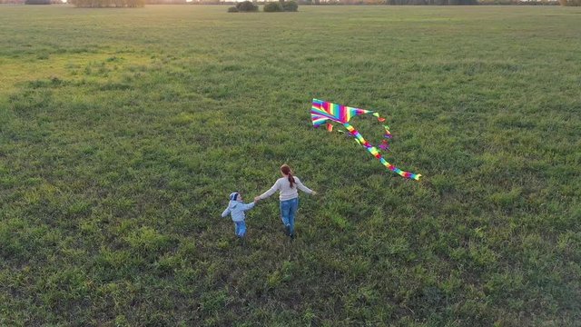 The mother and boy run with a kite on a green field. Laughter and joy, festive mood. Autumn,Sunset