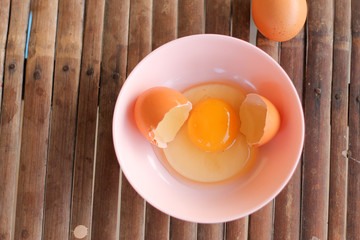 shell with egg and open Eggs in a pink bowl on Bamboo battens. Top view closeup