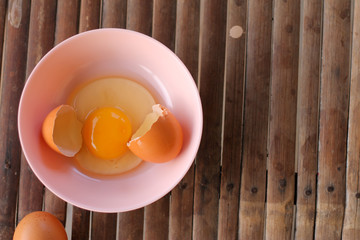 shell with egg and open Eggs in a pink bowl on Bamboo battens. Top view closeup
