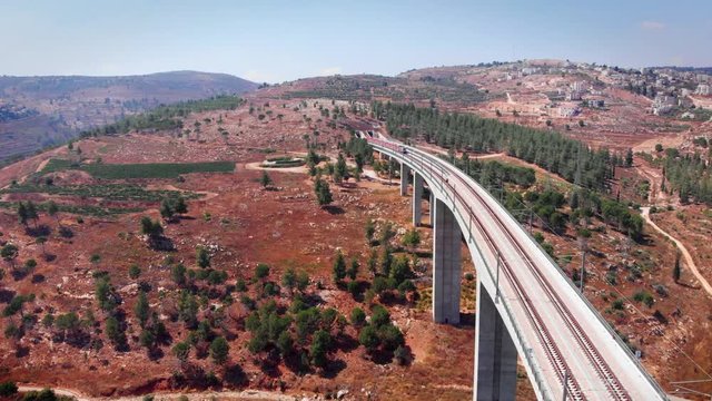 Aerial footage of Modern passenger train crossing a bridge and entering tunnel Train on Large bridge entering tunnel drone fotage