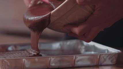 Baking brownies - pouring chocolate mixture into baking tray in kitchen 