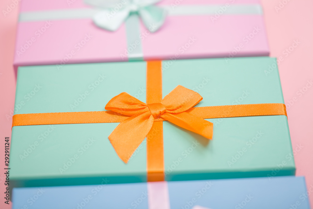 Poster multi-colored boxes with bows on a pink background