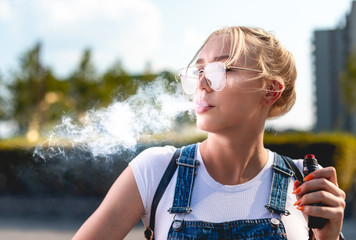 Portrait of young woman vape an electronic cigarette outdoor