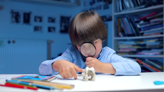Home education, self-isolation at home COVID-19. Mental relocation of children. Schoolboy examines an object through a magnifying glass.