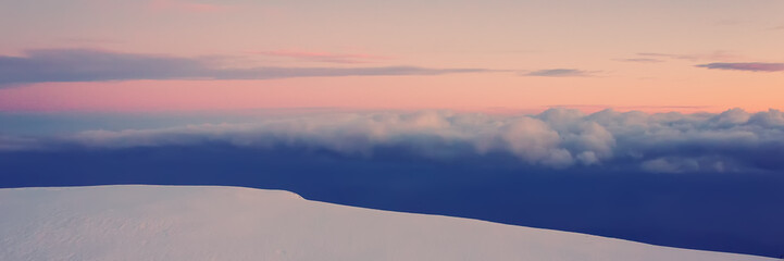 Snow in the mountains, clouds and sky in the evening, panoramic.