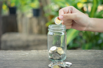 Businessmen Put the coin in a glass jar To save money, save money on investments, spend money when needed And use in the future. Investment concept. Savings with copy spaces.