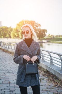 beautiful stylish girl with white hair in an autumn coat, photographed in a city park