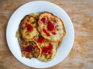 Top view on a plate with zucchini pancakes flavored with mixed honey and raspberry mash